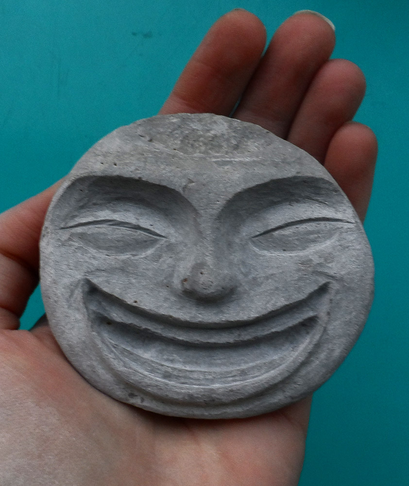 Galet dans lequel est sculpté un visage heureux qui rit