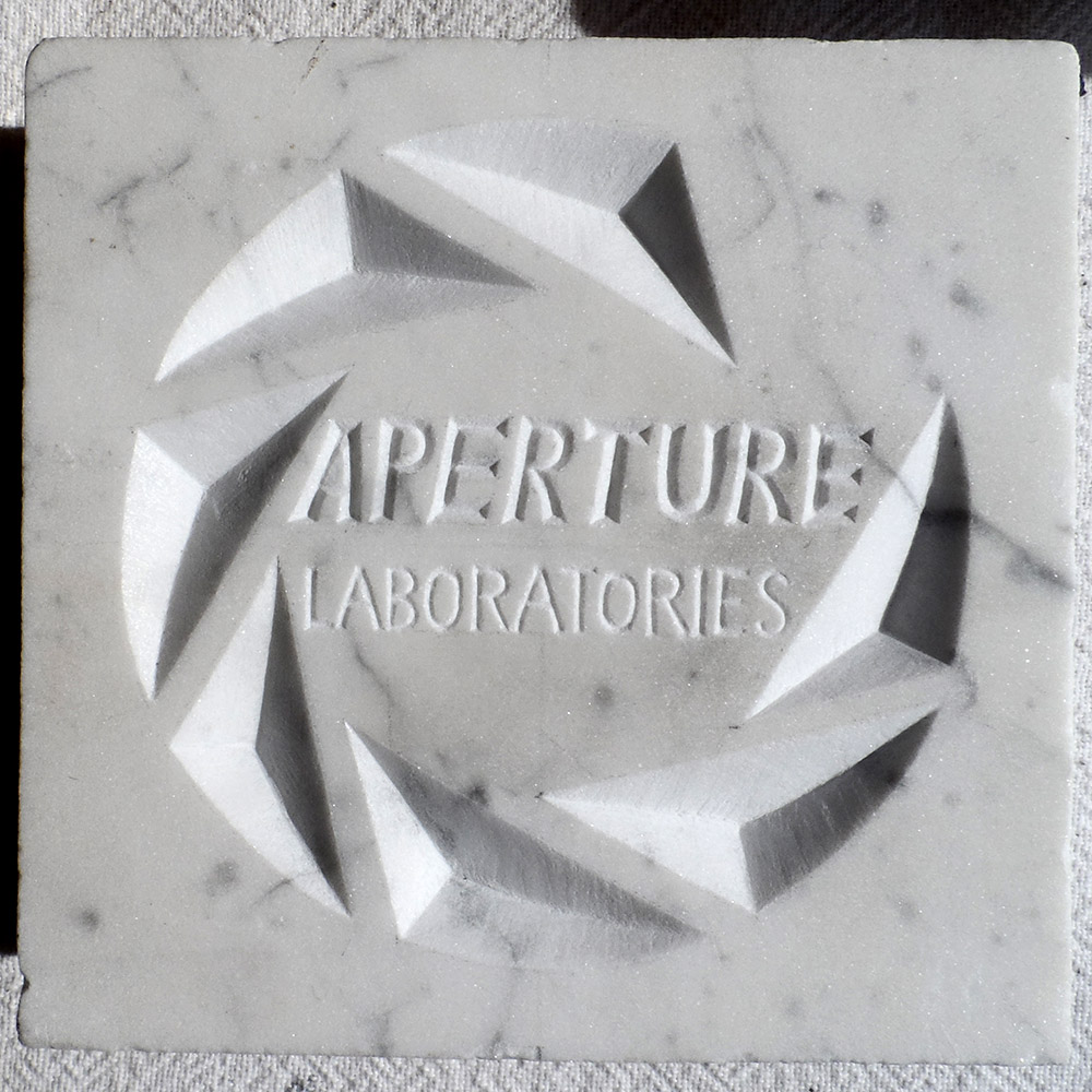 Logo de l'entreprise fictive Aperture Science (Portal) gravée en marbre blanc. We do it because we can.