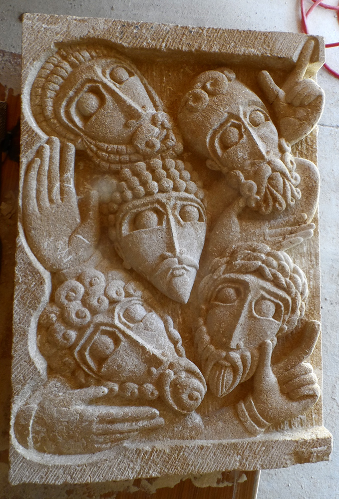 Bas-relief en pierre de dordogne représentant 5 visages et 5 mains entremêlés.