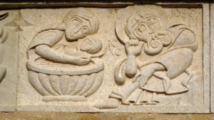 Bas-relief en calcaire de Brouzet-les-Alès jaune représentant la scène apocyphe du bain de l'enfant Jésus et les interrogations de saint Joseph