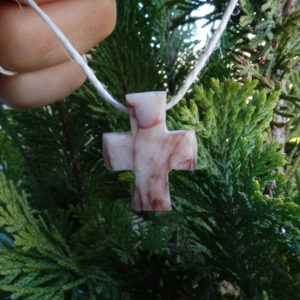 Pendentif en forme de croix dans un galet blanc veiné de rouge.